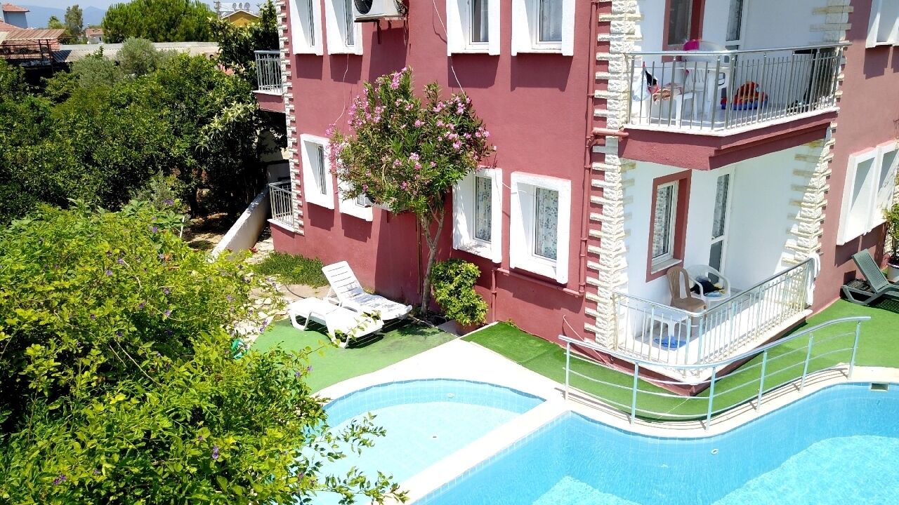 Un immeuble à plusieurs étages doté d’une piscine, de balcons et d’espaces extérieurs aménagés pour s’asseoir.