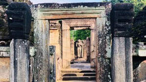 Una estructura de piedra antigua con un arco central que conduce a una estatua.