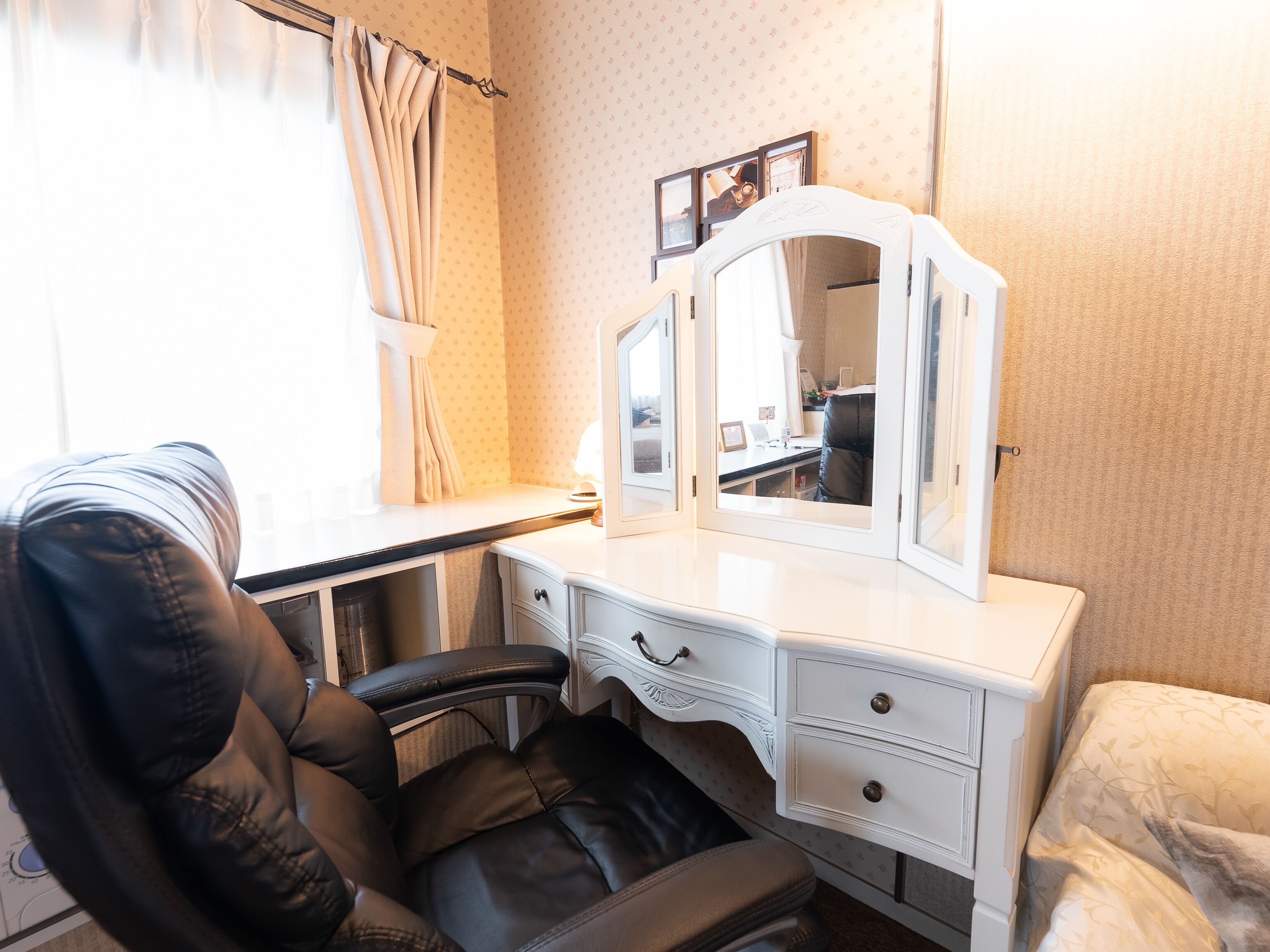 Une chambre d’hôtel équipée d’un bureau, d’une chaise, d’une coiffeuse avec un miroir et d’un lit.