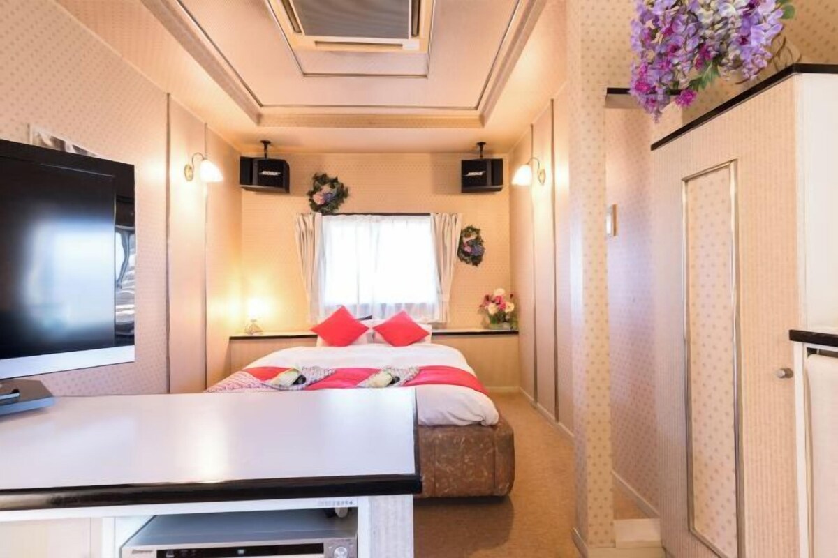 A hotel room with a bed, a TV, a desk, and a wardrobe.