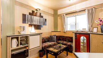 A compact living space with a kitchenette, a sofa, a coffee table, and a window with curtains.