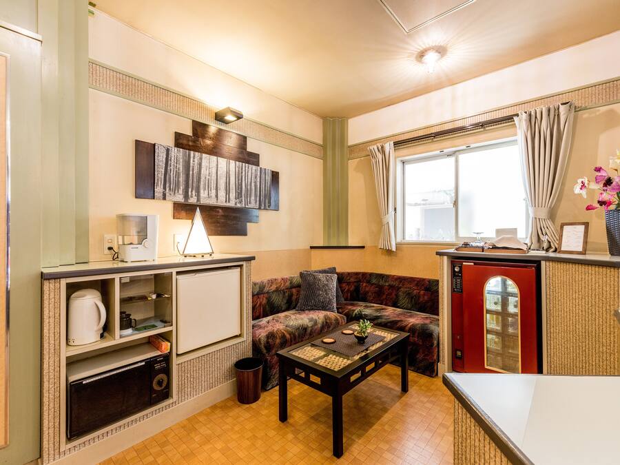 A compact living space with a kitchenette, a sofa, a coffee table, and a window with curtains.