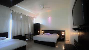 A hotel room with two beds, a ceiling fan, a TV, and a nightstand with a lamp.