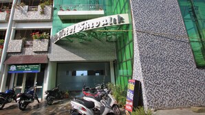A hotel with a green facade, multiple balconies with potted plants, and a sign indicating a 24-hour ATM. - Hotel Shivalik - Best Himalaya View Hotel In Almora' (Almora)