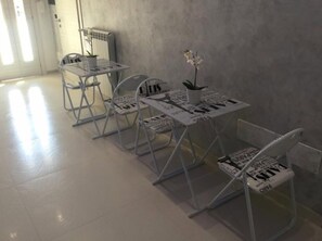 A minimalist room with metal-framed tables and chairs, a radiator, and a potted orchid. - B&B Vittorio Emanuele (Licata)