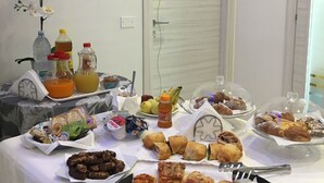 Una mesa de buffet con diversos alimentos, entre ellos pizzas, pasteles y salsas.