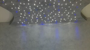 Una habitación de hotel con una cama grande, dos mesitas de noche con lámparas y un techo con luces pequeñas.