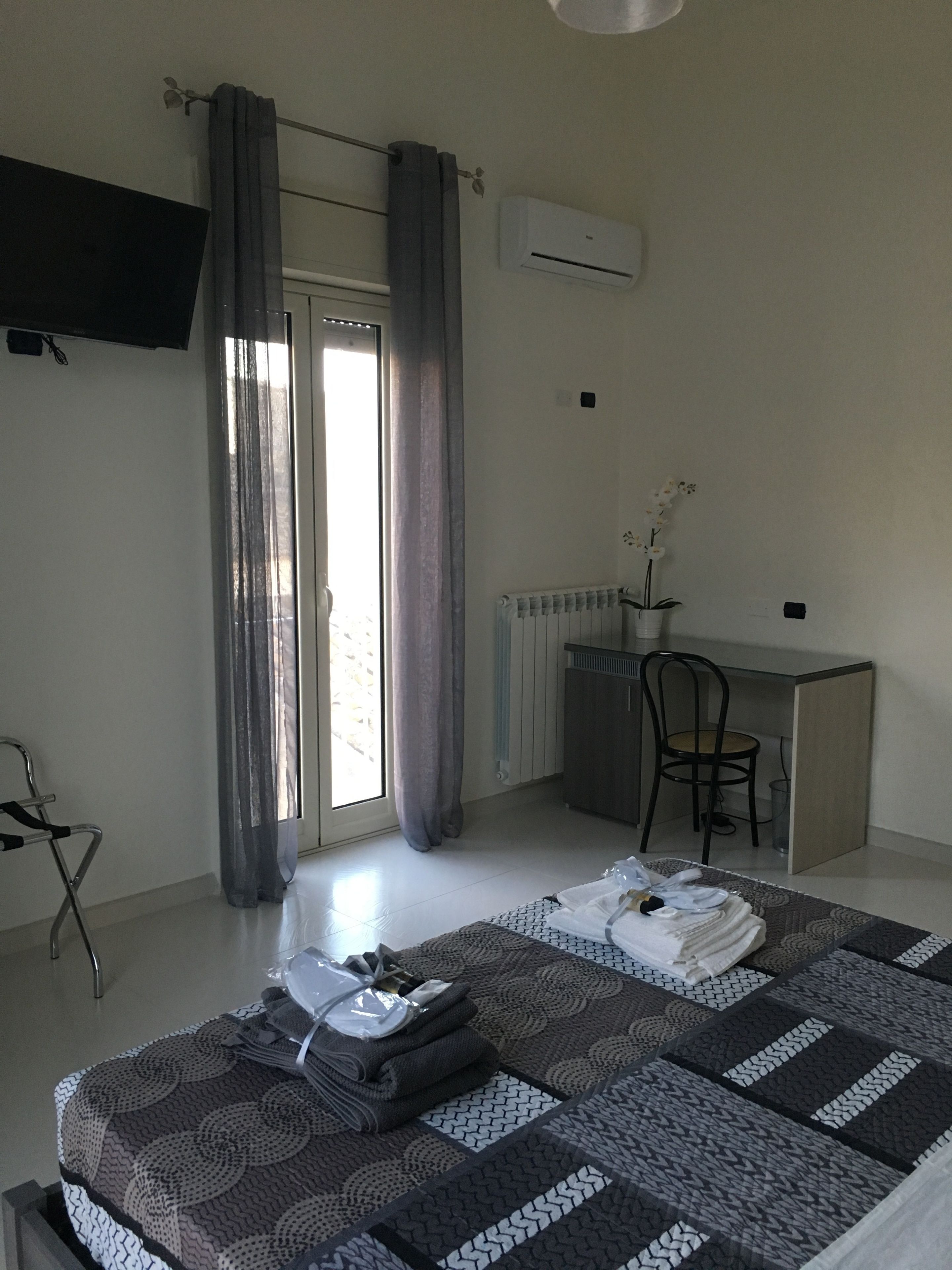 A bedroom with a bed, a desk, a chair, and a radiator.