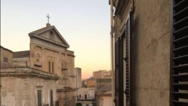 Una calle estrecha con edificios históricos, incluyendo una iglesia con una cruz en la parte superior.