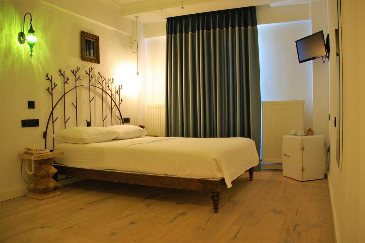 Une chambre à coucher avec un lit en bois, une table de chevet, un téléviseur fixé au mur et un radiateur.