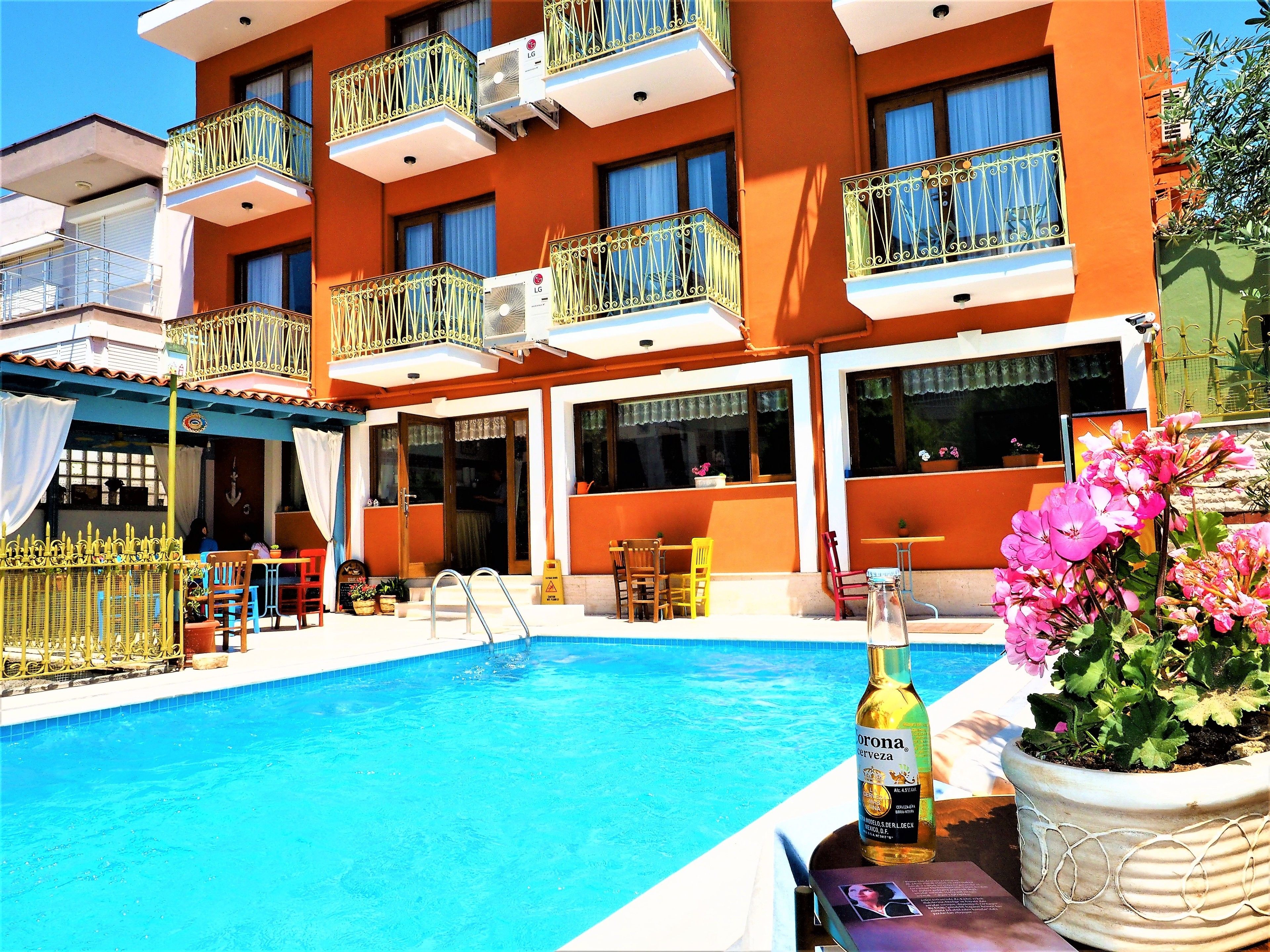 Ein Hotel mit Schwimmbad, Außenbereich zum Sitzen und Balkonen mit Klimaanlagen.