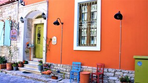 A building with a green door, a window with decorative iron bars, and potted plants on the ground. - Foca 1887 Otel (Foça)