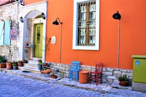 A building with a green door, a window with decorative iron bars, and potted plants on the ground.