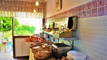 A kitchen with a variety of cooking utensils, a toaster, and a window with a view of greenery.