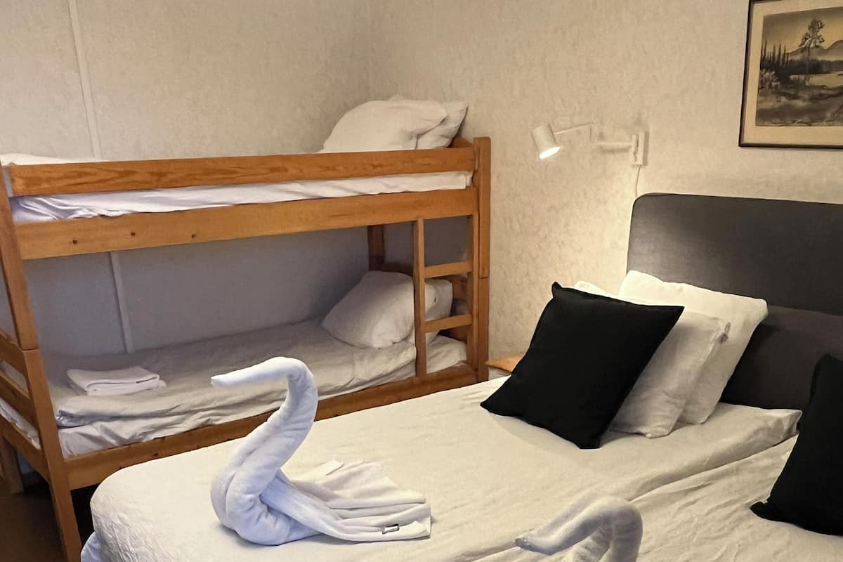 Une chambre d’hôtel avec un grand lit, un lit superposé en bois et un tableau au mur.