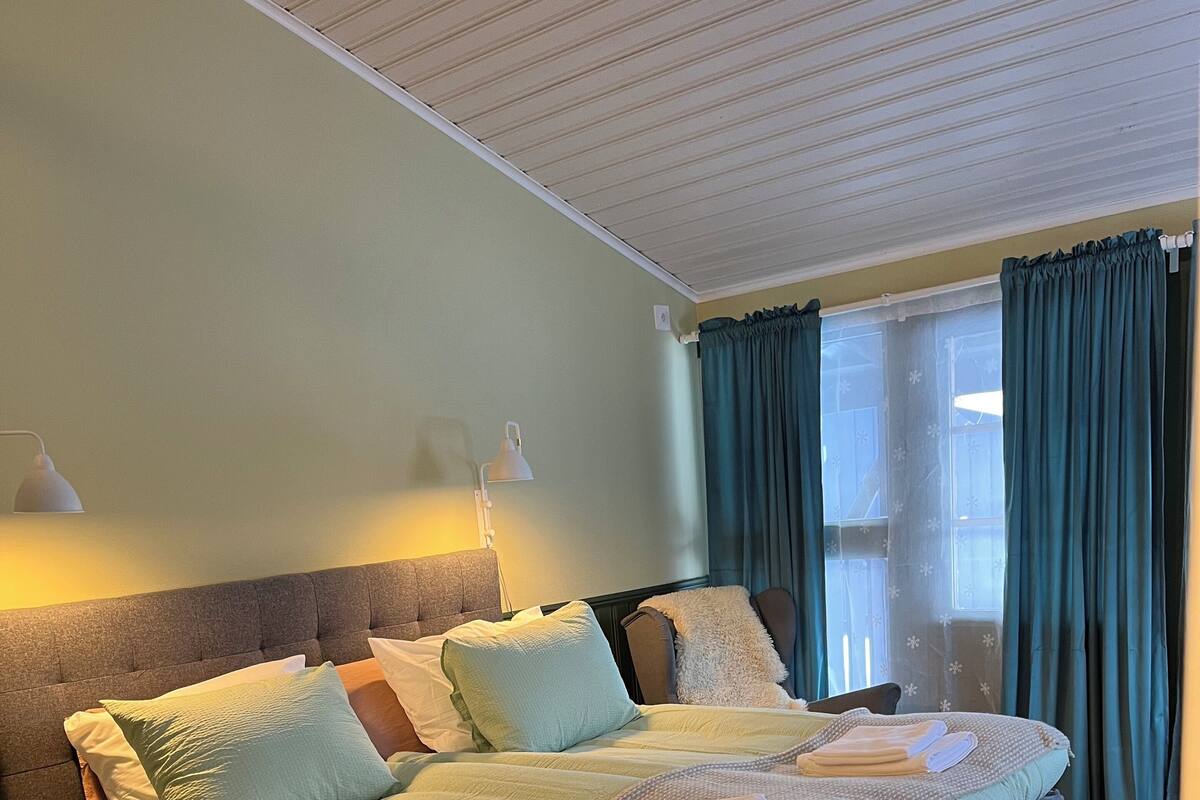Un lit bien fait, avec plusieurs oreillers et une couverture, une lampe de chevet et une table de chevet.
