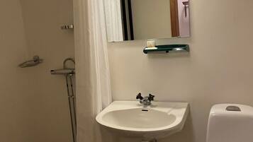Un baño con un lavamanos blanco, un espejo, un inodoro y una cortina de ducha.