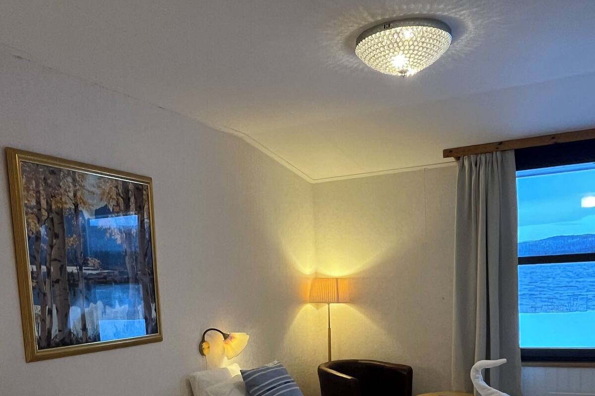 Une chambre d’hôtel avec deux lits, un tableau, une lampe et une vue sur la mer.