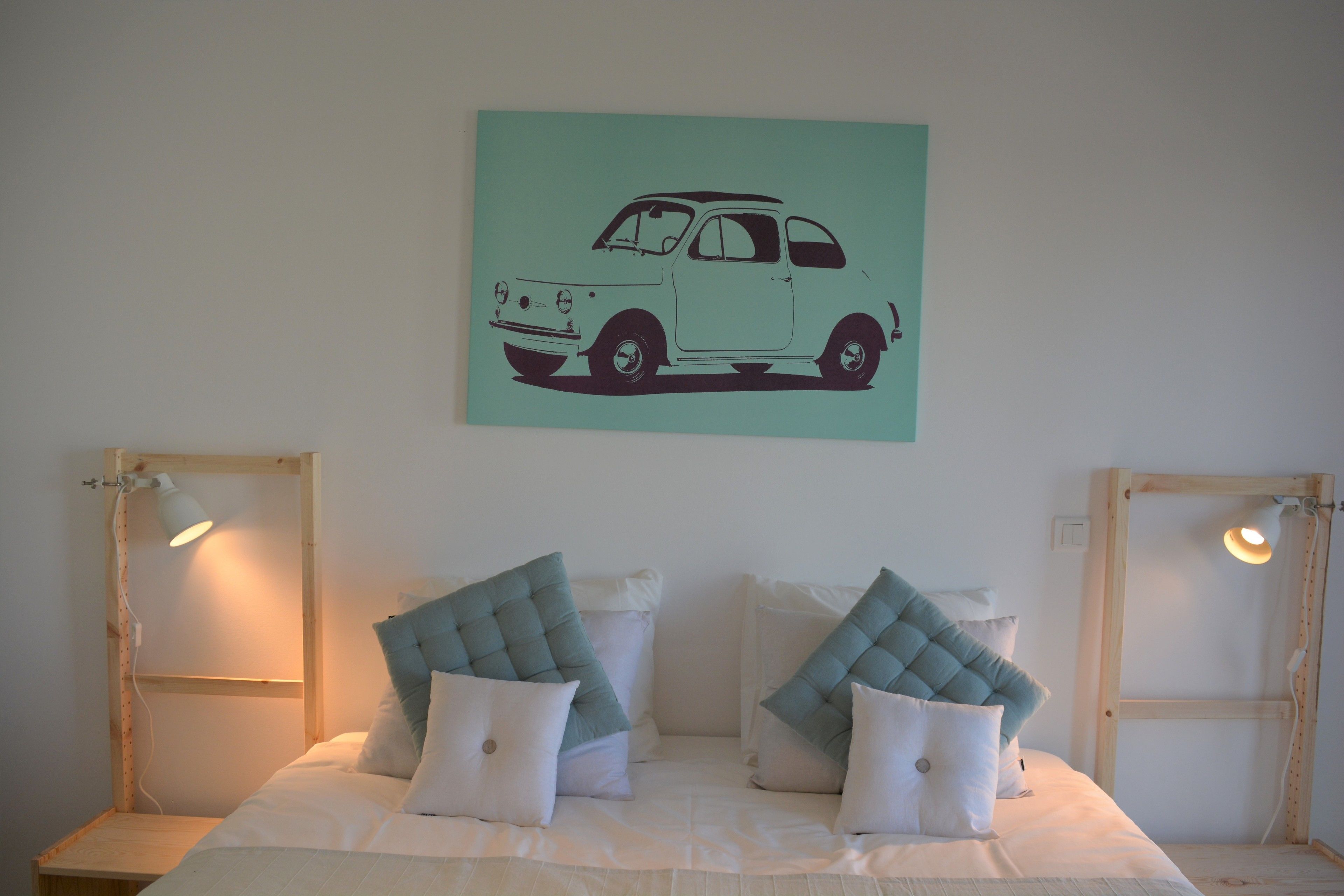 A bedroom with a bed, pillows, and a wall-mounted lamp.