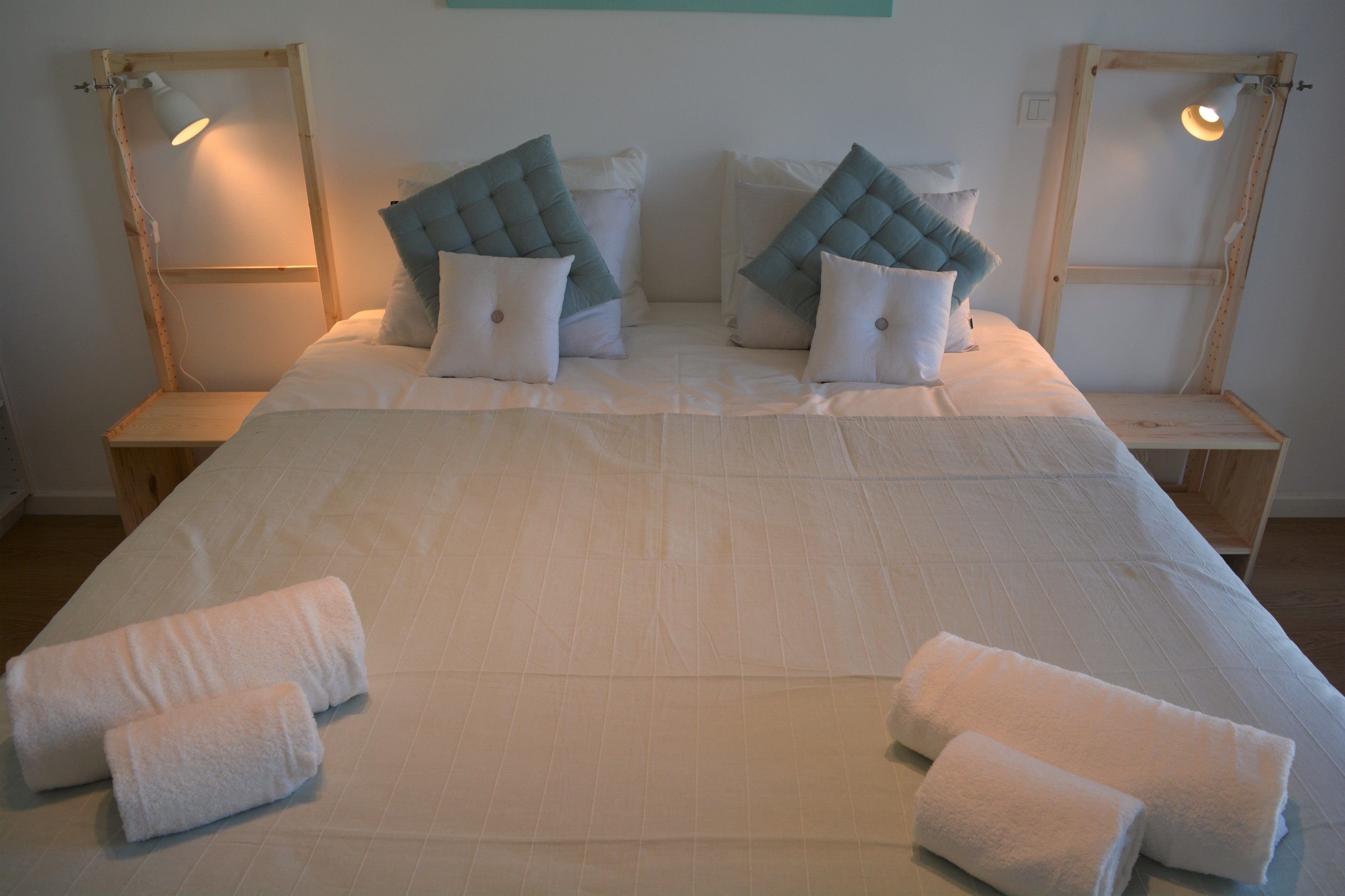 Una cama bien hecha con dos almohadas, dos mesitas de noche y dos lámparas.