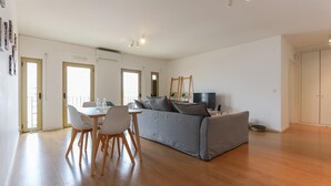 A spacious living area with a grey sofa, wooden dining table with chairs, and a television. - Modern & Bright by Homing (Lisbon)