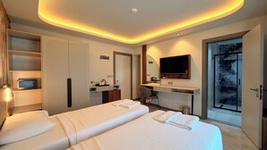 Een hotelkamer met twee bedden, een bureau, een douche en een televisie.