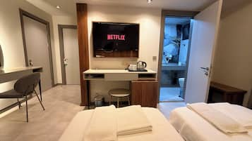 Habitación triple Deluxe | Área de sala de estar | Televisión LCD