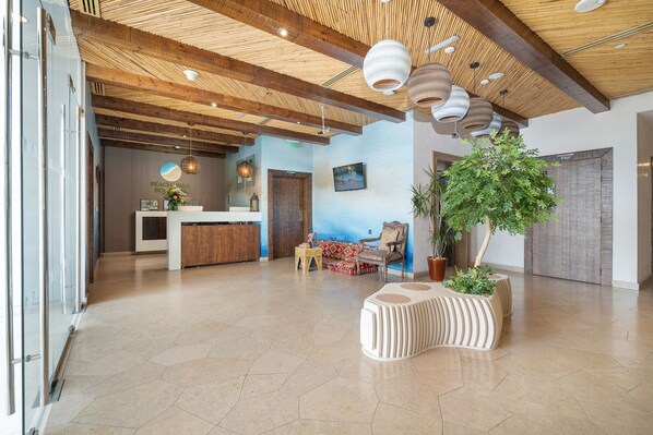 A spacious lobby with a reception desk, seating area, and a large potted plant.