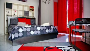 Une chambre moderne avec un lit, une chaise, une armoire et un rideau rouge.