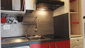 Une cuisine compacte équipée d’un four à micro-ondes, d’une cuisinière, d’un évier et d’un lave-linge.