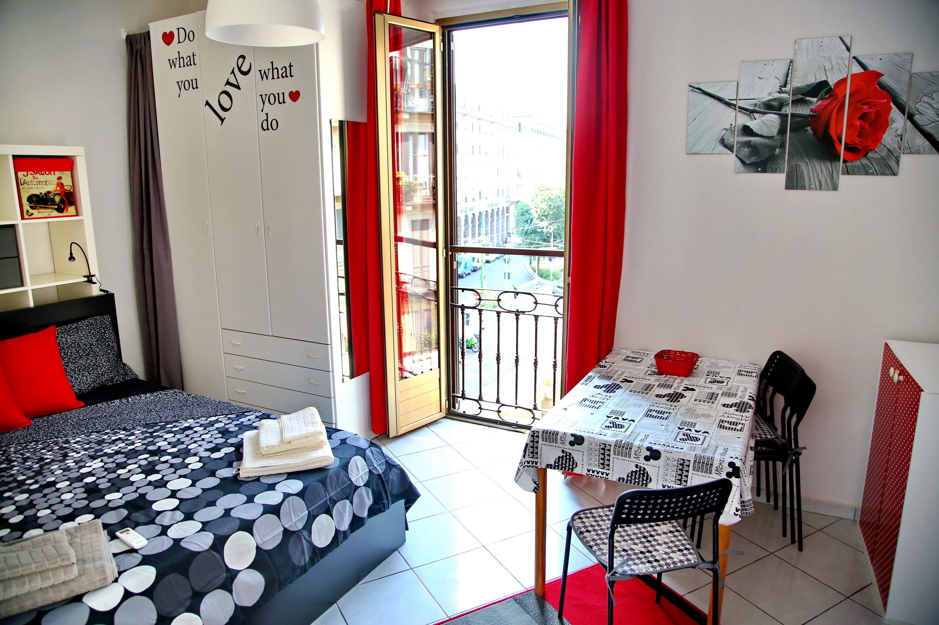 Un dormitorio con cama, escritorio y balcón.