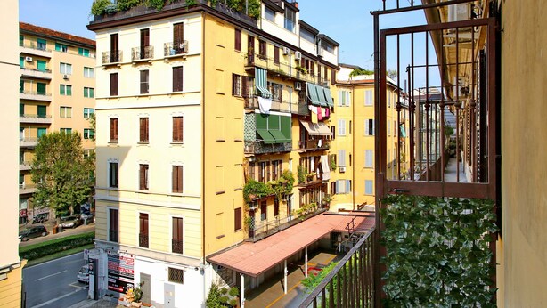 Un immeuble à plusieurs étages doté de balcons, avec une entrée au rez-de-chaussée bien visible et donnant sur la rue.