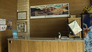 A wooden reception desk with a framed photograph of a building, a map, and a small statue. - Hostal Anas (Merida)