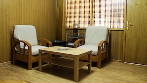 A room with two wooden chairs, a small table, and a window with plaid curtains. - Hostal Anas (Merida)
