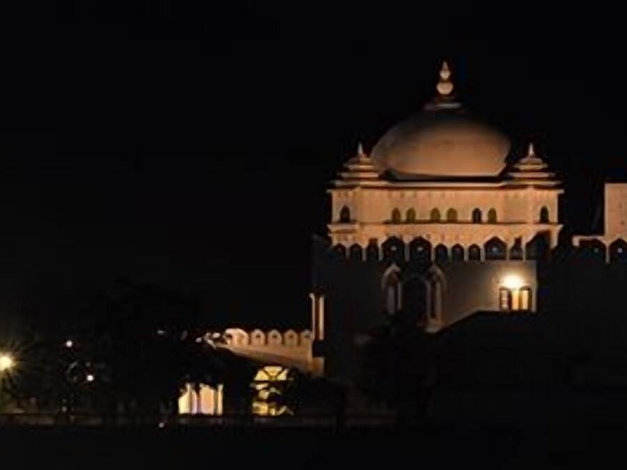 A large, illuminated building with a prominent dome and arched windows at night.
