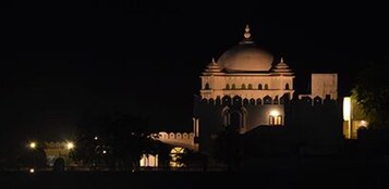 Un grande edificio illuminato, con una cupola imponente e finestre ad arco, di notte.