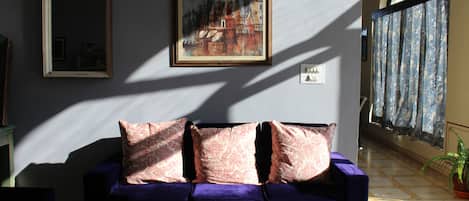 A room with a purple sofa, a chessboard, and a painting on the wall.