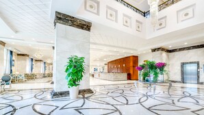 Un vestíbulo amplio con piso de mármol, una mesa de recepción y una escalera.