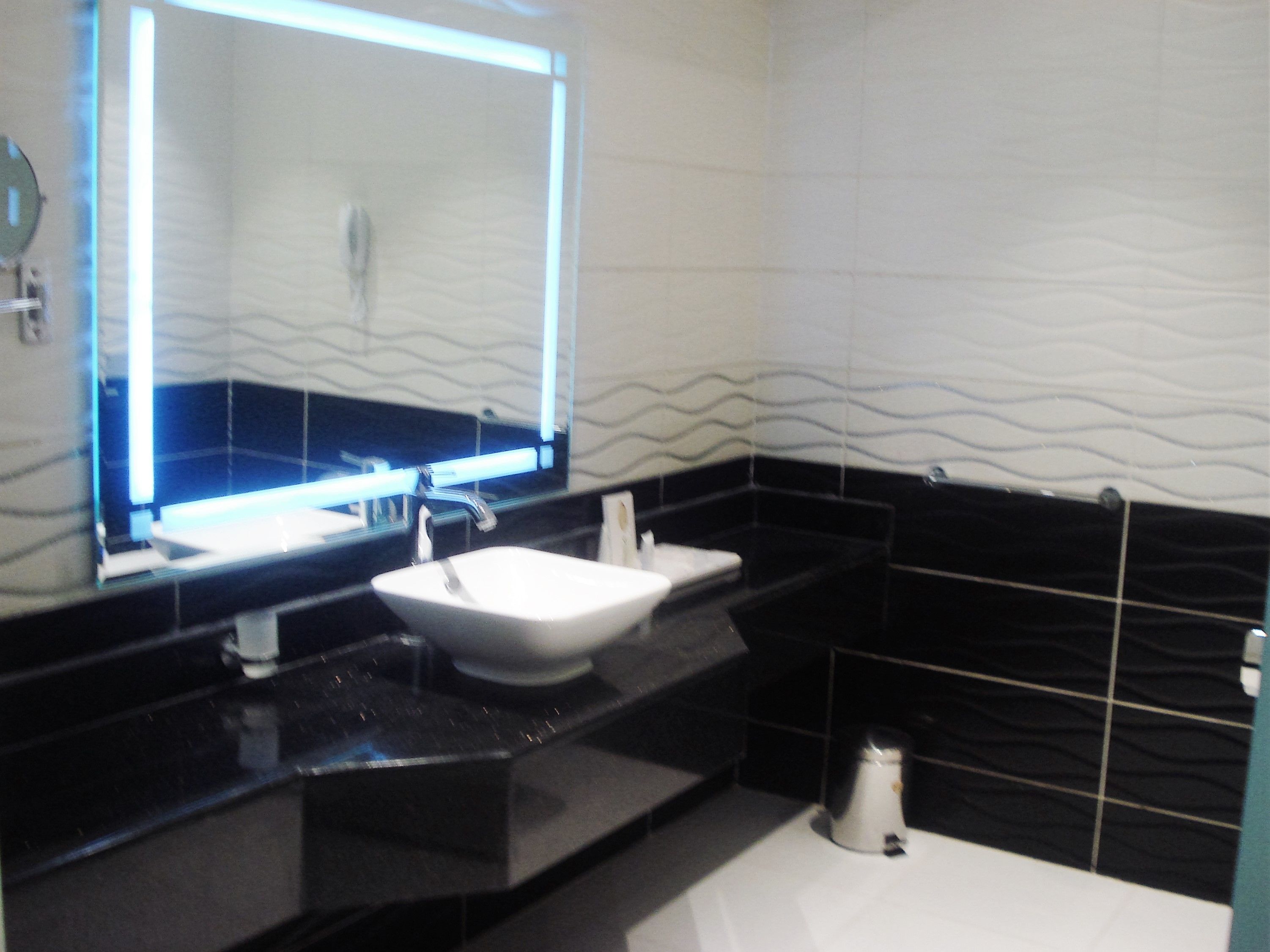 A bathroom with a white sink, black countertop, and a mirror above it.