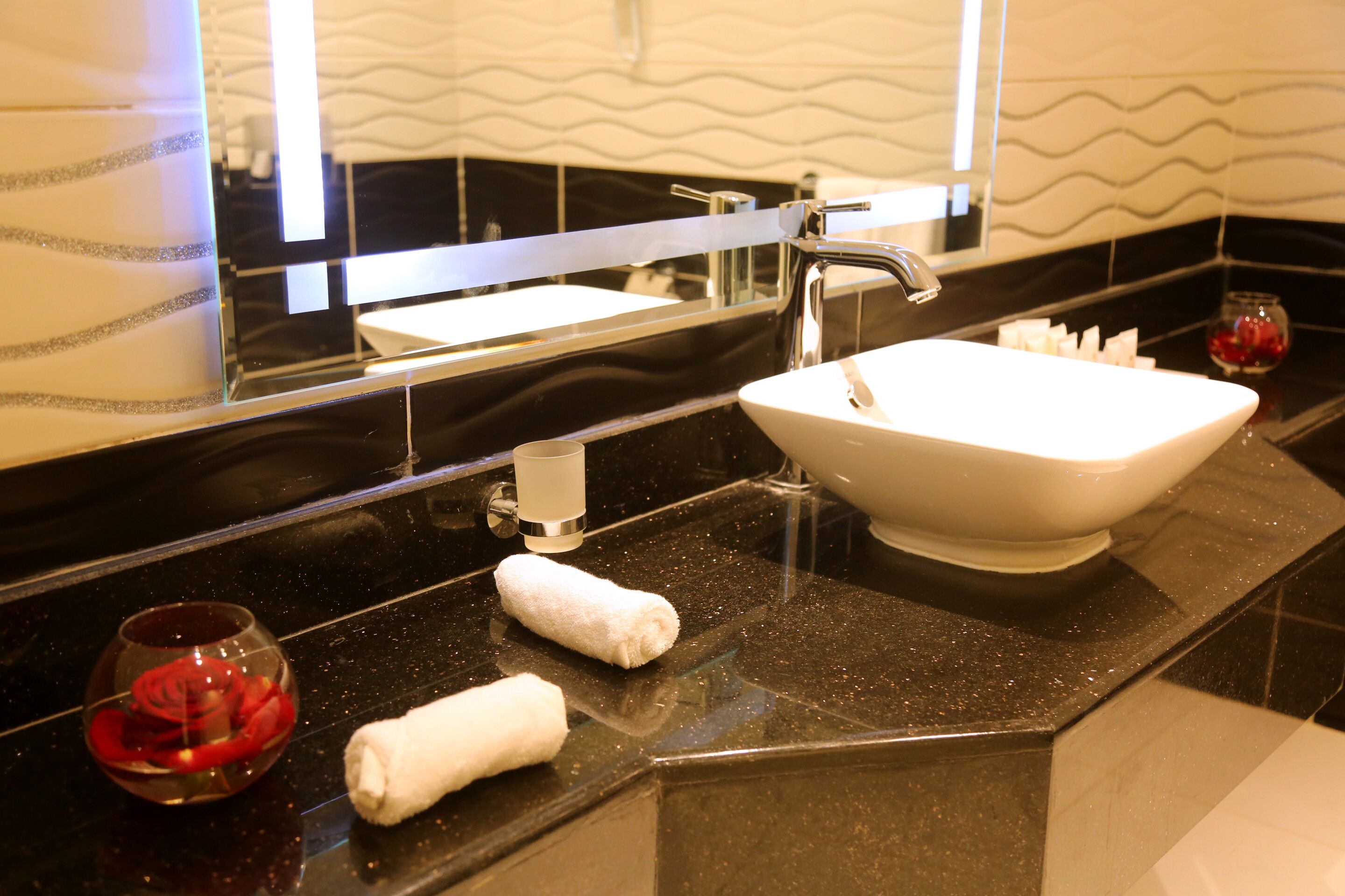 A modern bathroom with a black countertop, a white sink, and a mirror above it.