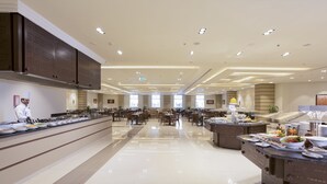 Un comedor amplio y bien iluminado en un hotel, con varias mesas y una barra de buffet.