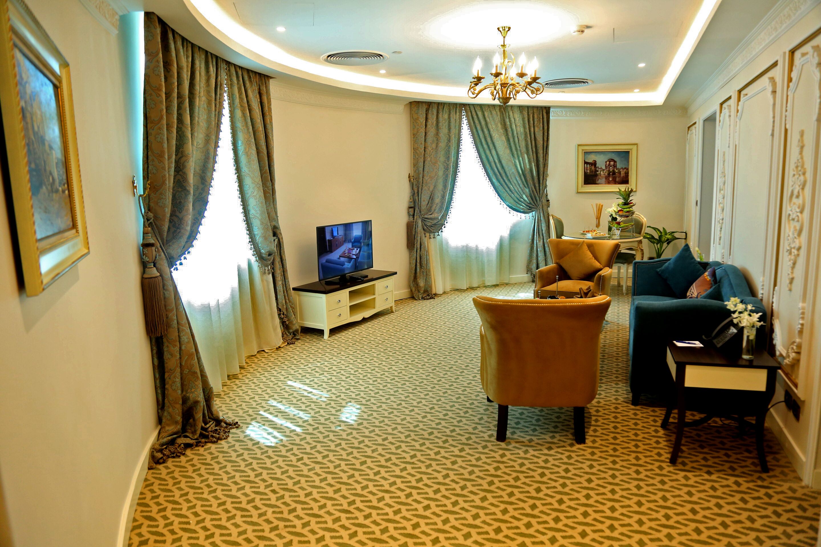 Una sala de estar con televisión, un sofá, una silla y una mesa con un jarrón.