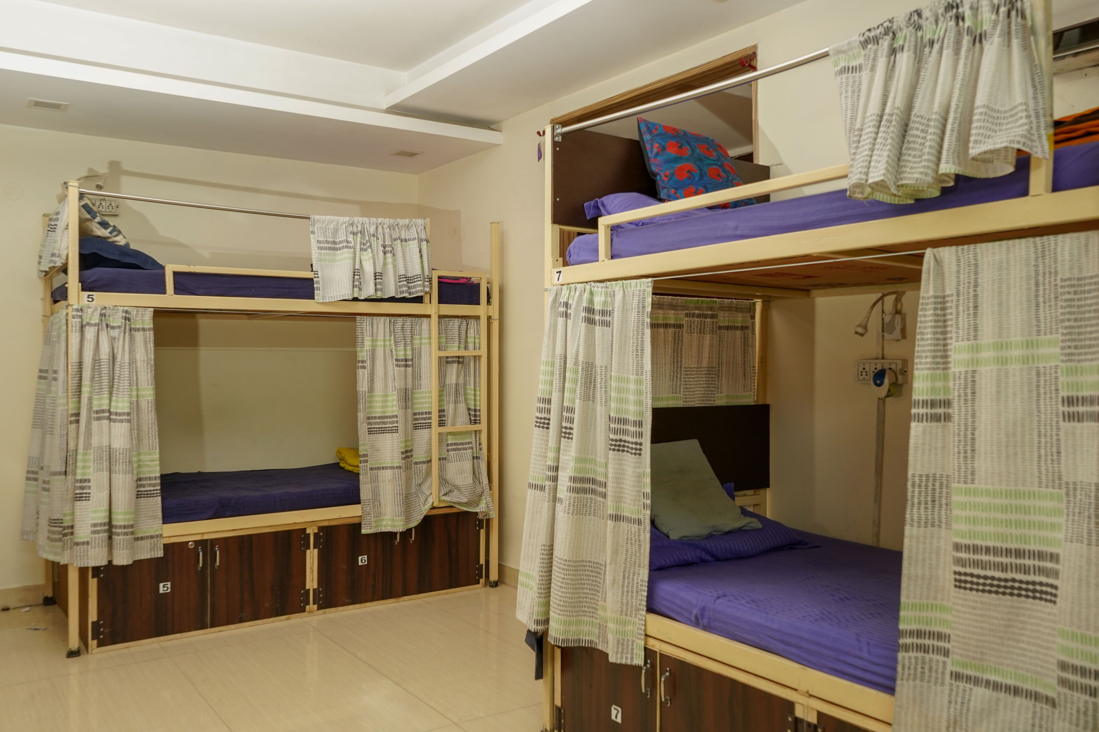 Ein Schlafsaalzimmer mit Etagenbetten, Vorhängen und einem kleinen Schreibtisch mit Lampe.
