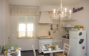 A compact kitchen with a gas stove, a refrigerator, and a dining area with a table set for breakfast.