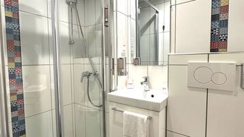 A modern bathroom with a glass-enclosed shower, a white sink, and a toilet.