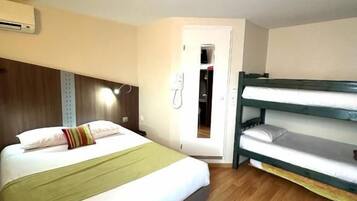 A room with a bed, a bunk bed, wooden flooring, a wall-mounted air conditioner, and a door leading to another room.