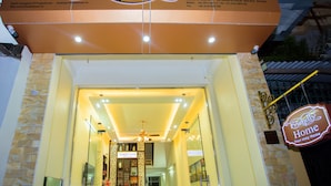 L’entrée d’un hôtel, avec une enseigne indiquant « Accueil chaleureux » et les coordonnées.