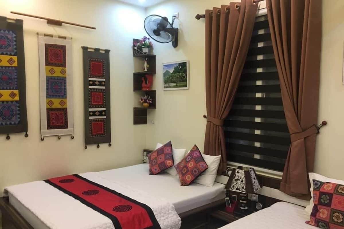 Un dormitorio con dos camas, un ventilador de pared y colchas decorativas.