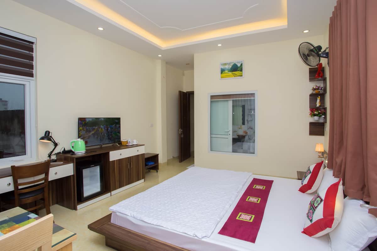 Una habitación de hotel con cama, escritorio, televisión y una pequeña kitchenette.