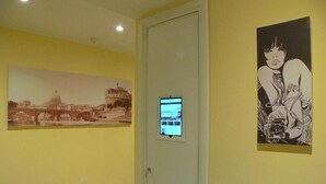 A hallway with a door, a digital display, and two framed artworks on the walls. - Ager Vaticanus (Rome)